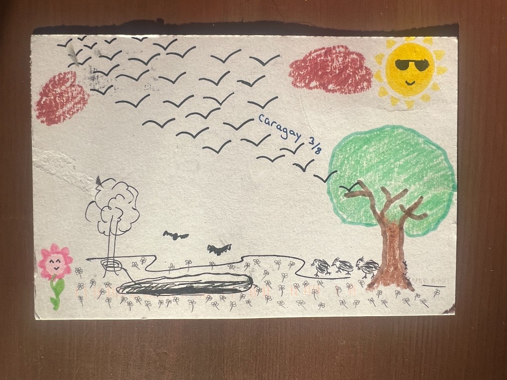 one postcard mailed back, outdoor scene drawn by hand with sun, birds, tree, and small figures in ink and crayon